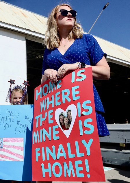 Kelly McGuire holds a sign for her husband, Nick, as VFA-22 lands Tuesday morning at NAS Lemoore after a long deployment.